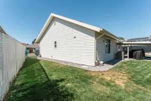 Back of property featuring a lawn and central AC