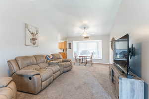 Carpeted living room with vaulted ceiling and ceiling fan