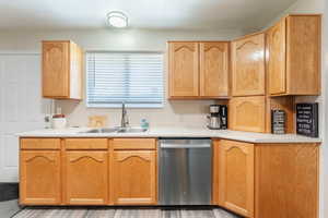 Kitchen with dishwasher, light hardwood / wood-style flooring, and sink