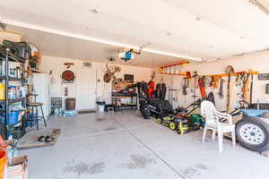 Garage with a garage door opener, a workshop area, and white fridge