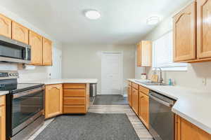 Kitchen featuring light hardwood / wood-style floors, a textured ceiling, sink, kitchen peninsula, and stainless steel appliances