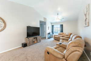 Living room featuring vaulted ceiling, ceiling fan, and light colored carpet