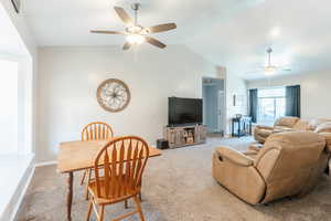 Living room featuring carpet floors, vaulted ceiling, and ceiling fan