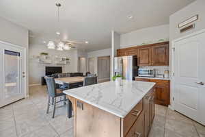 Kitchen featuring appliances with stainless steel finishes, decorative backsplash, a kitchen island, pendant lighting, and an inviting chandelier