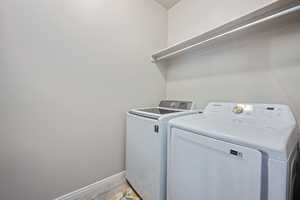 Washroom featuring washing machine and dryer and light tile patterned flooring