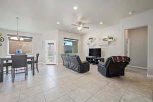 Living room with ceiling fan with notable chandelier and light tile patterned floors