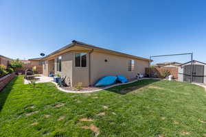 Back of house with a patio, a lawn, and a storage unit