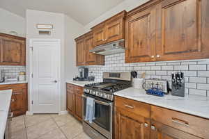 Kitchen with gas range, light tile patterned floors, and tasteful backsplash