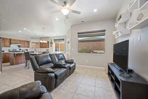 Tiled living room featuring ceiling fan with notable chandelier