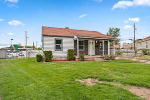 View of front facade featuring covered porch and a front yard