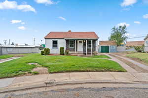 View of front of property with a storage shed, a front lawn, and covered porch