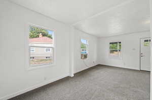 Carpeted spare room featuring a textured ceiling and a wealth of natural light