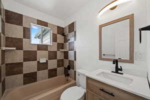 Full bathroom featuring tiled shower / bath, vanity, and toilet