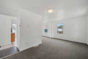 Carpeted spare room featuring a textured ceiling and cooling unit