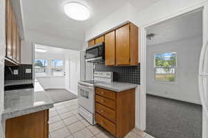 Kitchen with a textured ceiling, a healthy amount of sunlight, white electric range, and light tile patterned floors