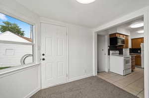 Kitchen with white appliances, light colored carpet, and tasteful backsplash