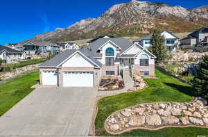 View of front of home featuring a mountain view, a garage, and a front lawn