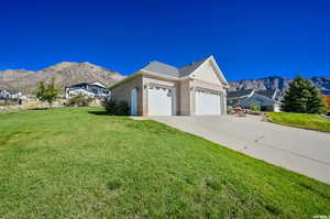 View of side of property featuring a yard, a garage, and a mountain view