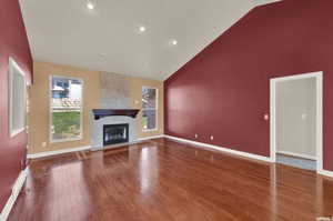 Unfurnished living room with a fireplace, dark wood-type flooring, and high vaulted ceiling