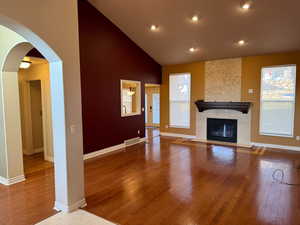 Unfurnished living room featuring hardwood / wood-style floors, a fireplace, and a healthy amount of sunlight