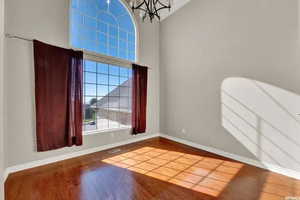 Empty room with a towering ceiling, a notable chandelier, and hardwood / wood-style flooring