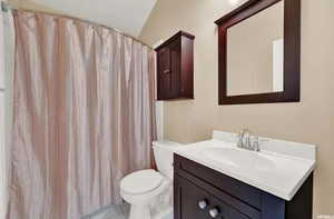 Bathroom featuring vanity, walk in shower, tile patterned flooring, toilet, and lofted ceiling