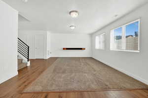 Unfurnished living room featuring a textured ceiling and dark hardwood / wood-style floors