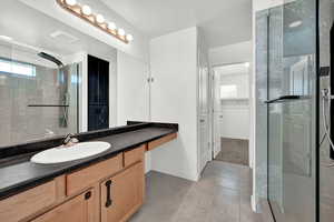 Bathroom featuring tile patterned flooring, a shower with door, and vanity