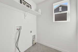 Laundry area with light tile patterned floors, electric dryer hookup, and washer hookup