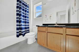 Full bathroom with vanity, toilet, shower / bathtub combination with curtain, and tile patterned floors