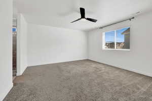 Spare room with ceiling fan, carpet floors, and a textured ceiling