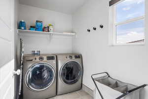 Laundry area with light tile patterned floors and washing machine and dryer