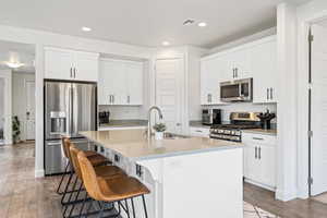 Kitchen featuring appliances with stainless steel finishes, sink, an island with sink, and hardwood / wood-style flooring