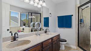 Bathroom with an inviting chandelier, walk in shower, tile patterned floors, vanity, and toilet