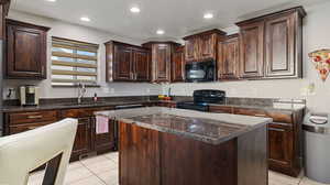 Kitchen with black appliances, a center island, light tile patterned flooring, and sink