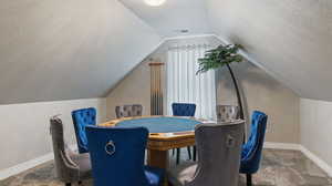 Carpeted dining room with lofted ceiling and a textured ceiling