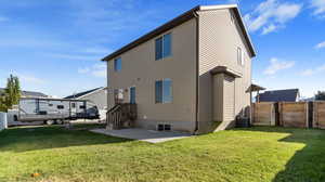 Back of property with cooling unit, a yard, and a patio