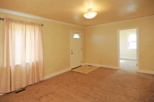 Entryway with carpet floors and crown molding