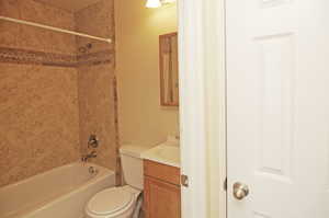 Full bathroom featuring tiled shower / bath, vanity, and toilet