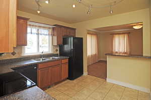 Kitchen featuring black refrigerator, tasteful backsplash, light tile patterned floors, and sink