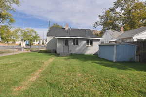 Rear view of property featuring a storage unit and a yard