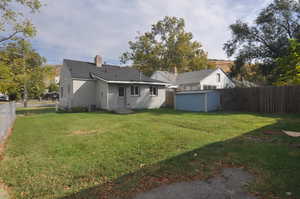 Back of house featuring cooling unit, a lawn, and a shed