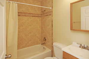 Full bathroom with vanity, toilet, and shower / bathtub combination with curtain