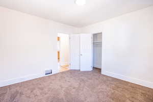 Unfurnished bedroom with light colored carpet and a closet