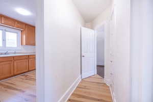 Hallway with light wood-type flooring and sink