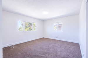 Empty room featuring a textured ceiling and carpet flooring