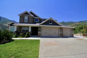 Craftsman house with a mountain view, a garage, a front yard, and covered porch