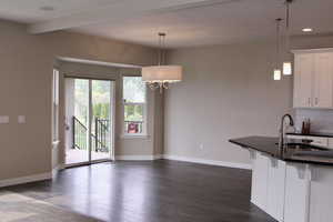 Kitchen featuring white cabinets, dark hardwood / wood-style floors, decorative light fixtures, and a breakfast bar area