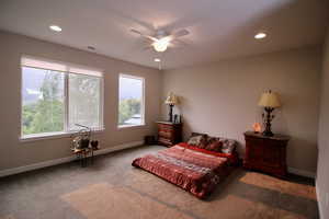 Upper floor main bedroom with multiple windows, ceiling fan, and carpet floors