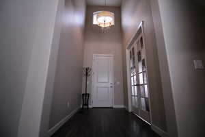 Interior space with an inviting chandelier, wood-style floors, and a towering ceiling